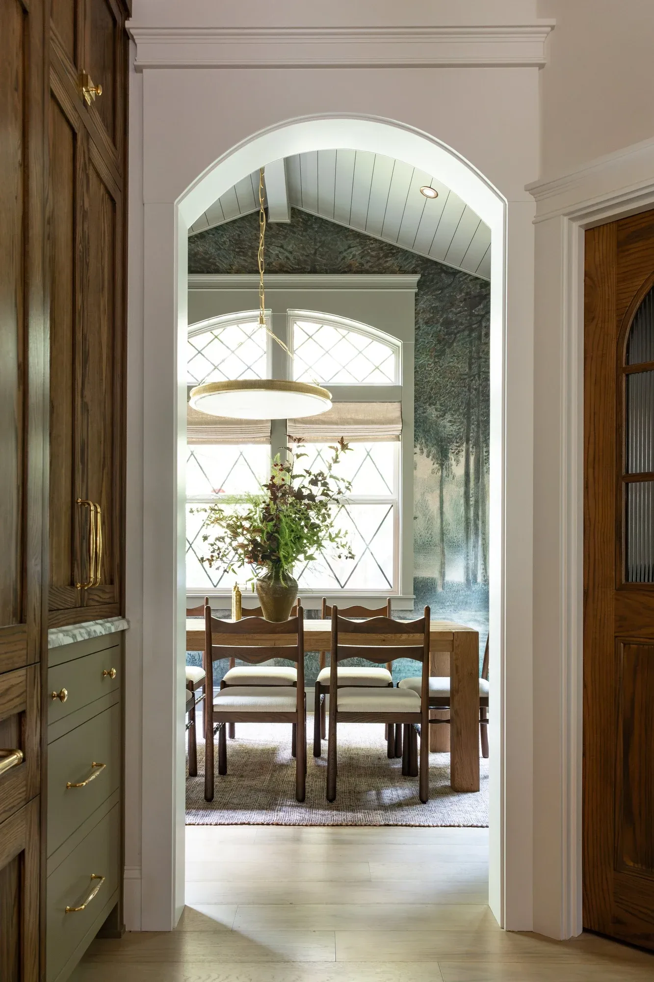 A view through an arched doorway to a dining room, an arrangement at the center of the table