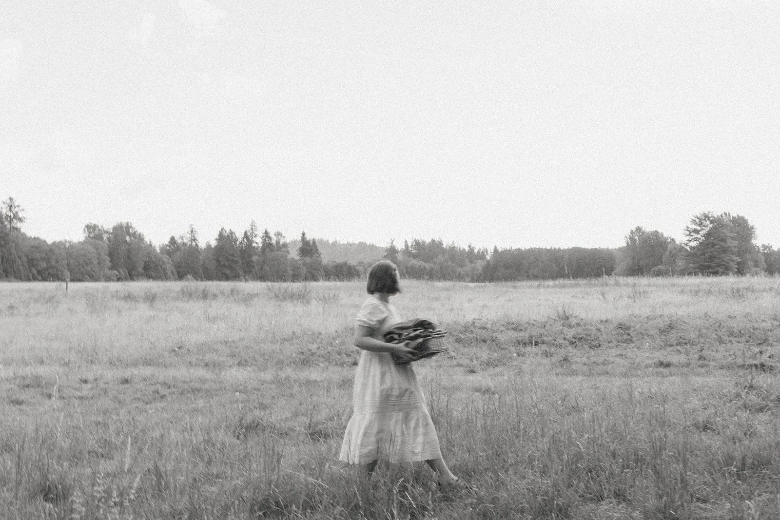 Dakotah walking through a tall-grass meadow carrying a basket