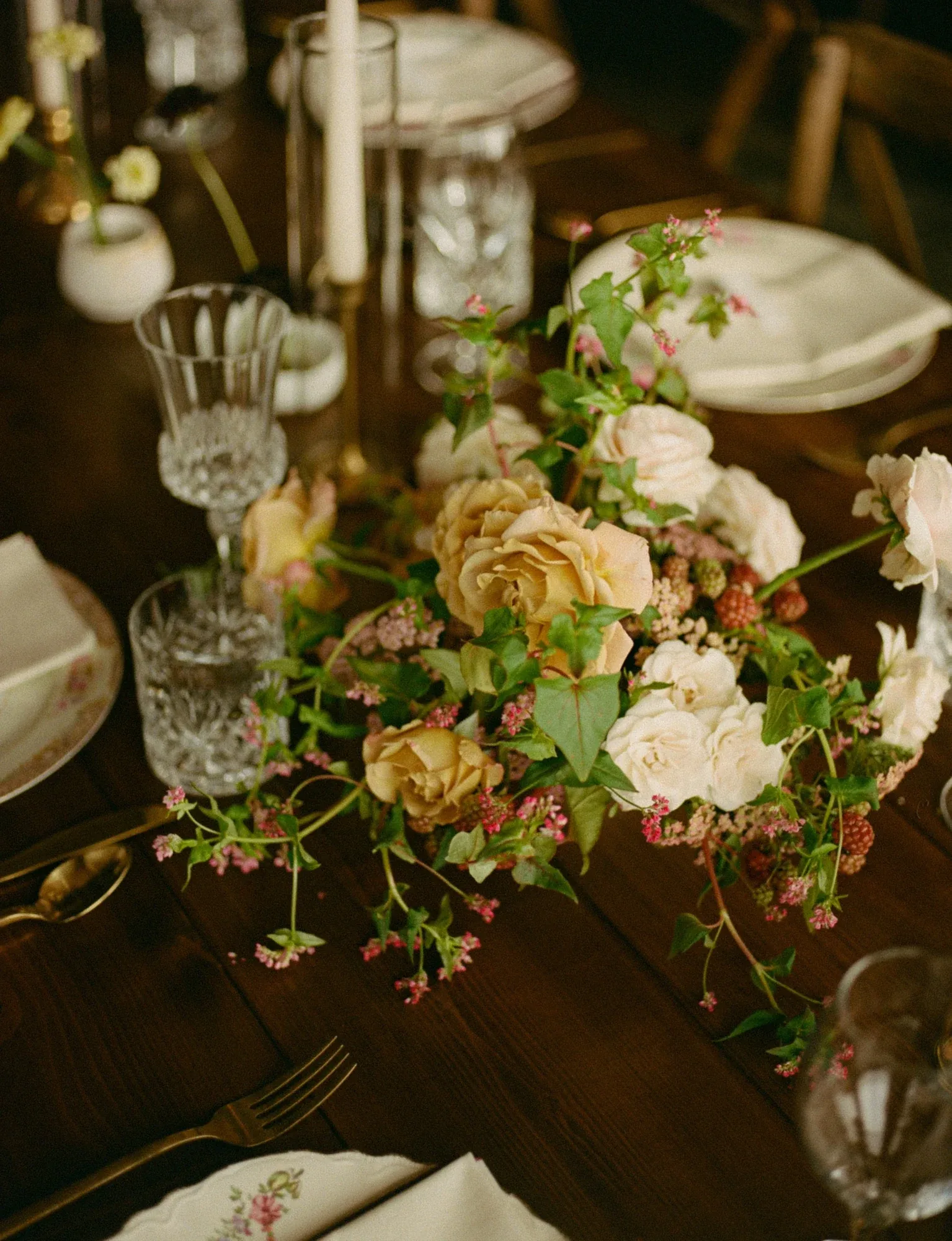 Garden roses and sweet peas trailing across a candlelit table set with vintage china and crystal