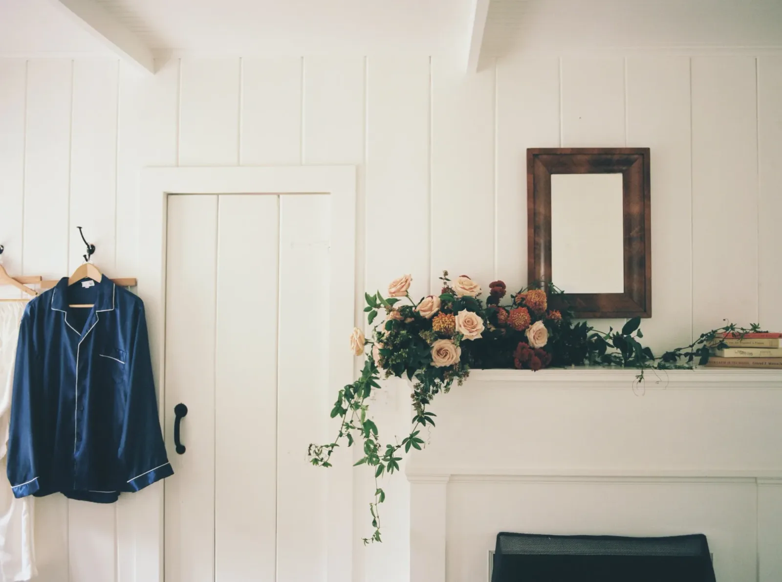 A garland of roses and trailing greenery along a white-painted mantel
