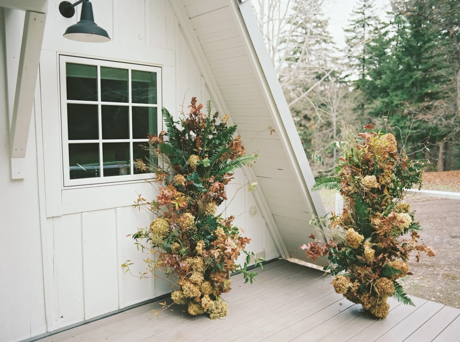 Twin dried-floral columns framing the doorway of a white A-frame